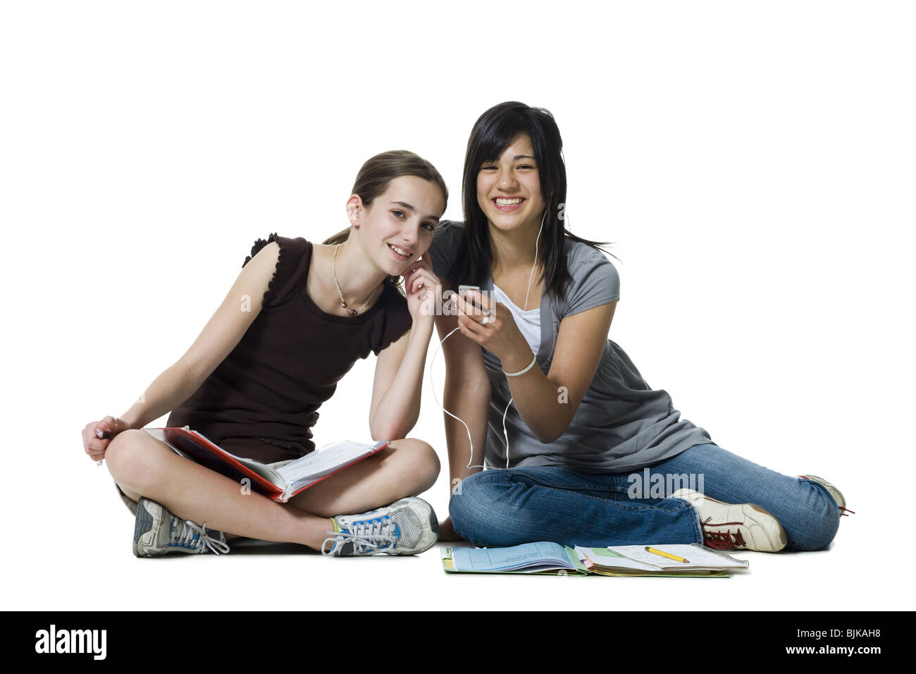 Zwei Mädchen sitzen Schneidersitz mit Hausaufgaben und MP3-player Stockfoto