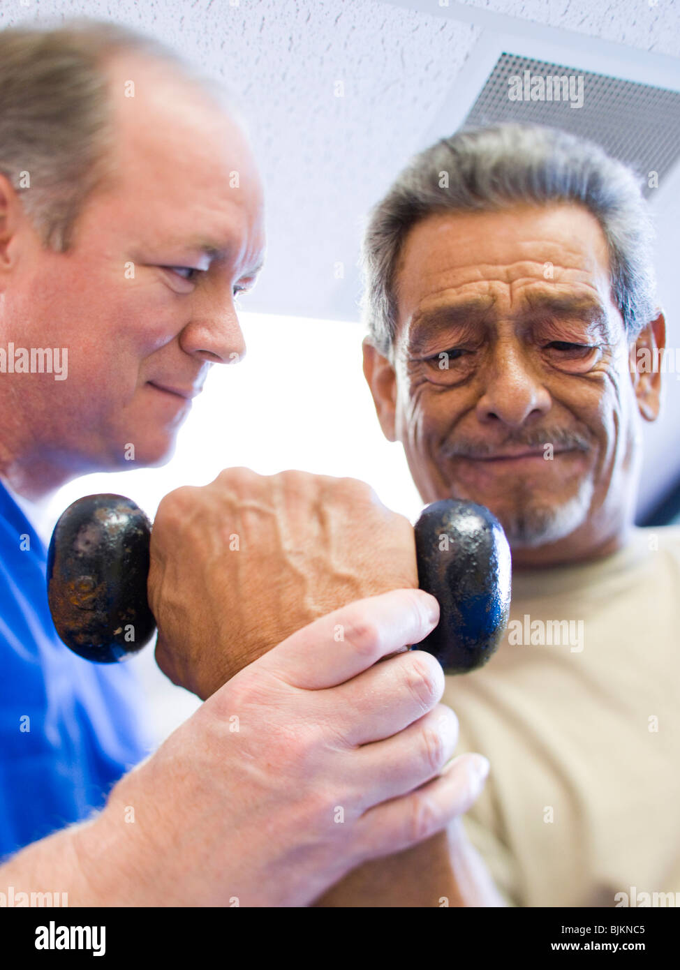 Physiotherapeuten, die Unterstützung eines Mannes mit Gewichten Stockfoto