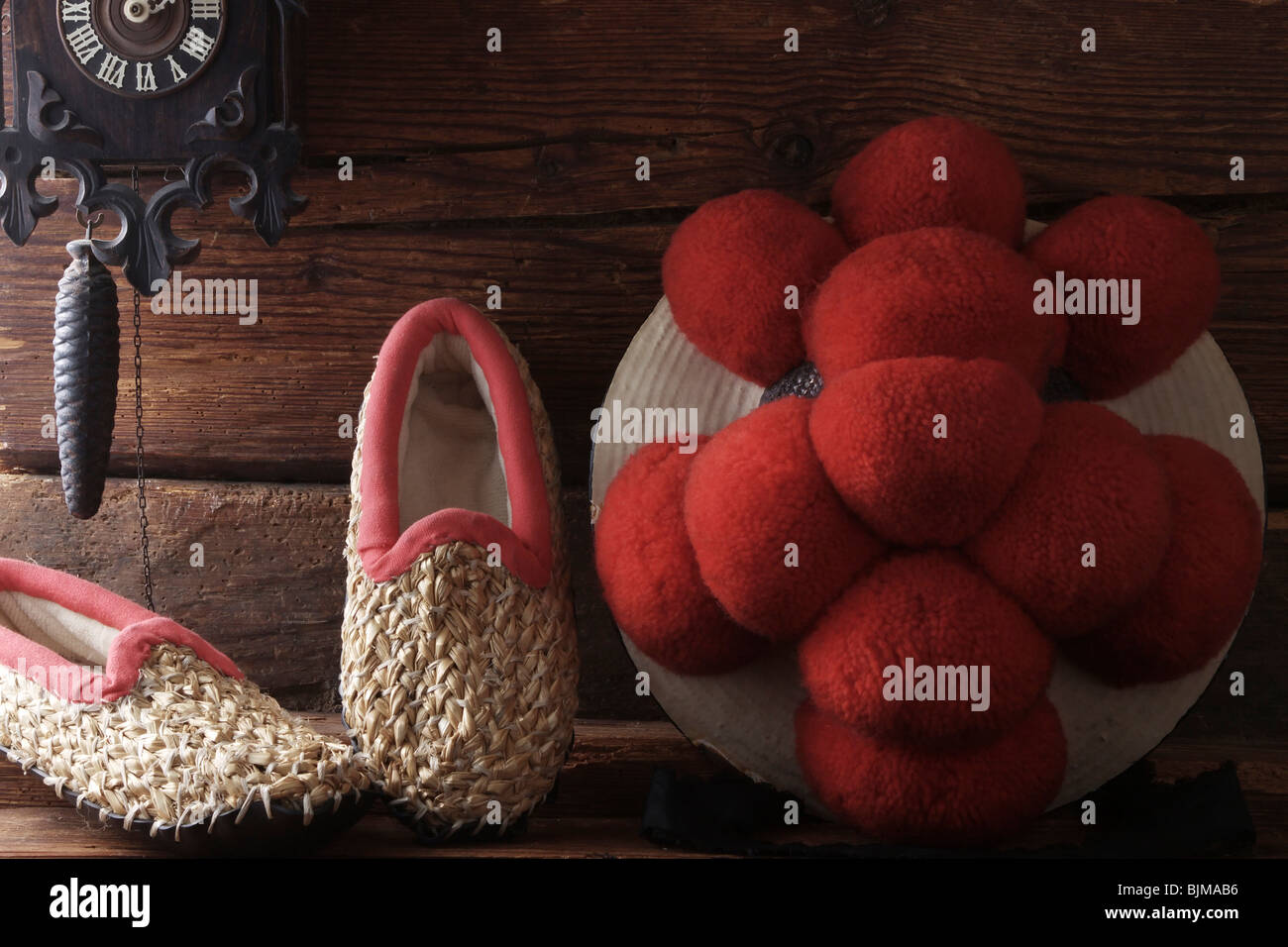 Bollenhut, Hut mit roten Pompons, Schwarzwald Tracht der unverheirateten Mädchen mit Stroh Pantoffeln auf einem rustikalen hölzernen ba Stockfoto
