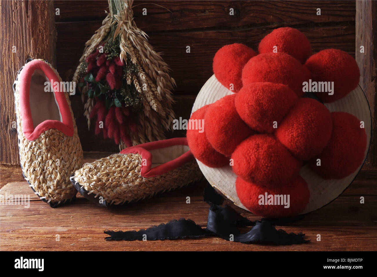 Bollenhut, Hut mit roten Pompons, Schwarzwald Tracht der unverheirateten Mädchen mit Stroh Pantoffeln auf einem rustikalen hölzernen ba Stockfoto