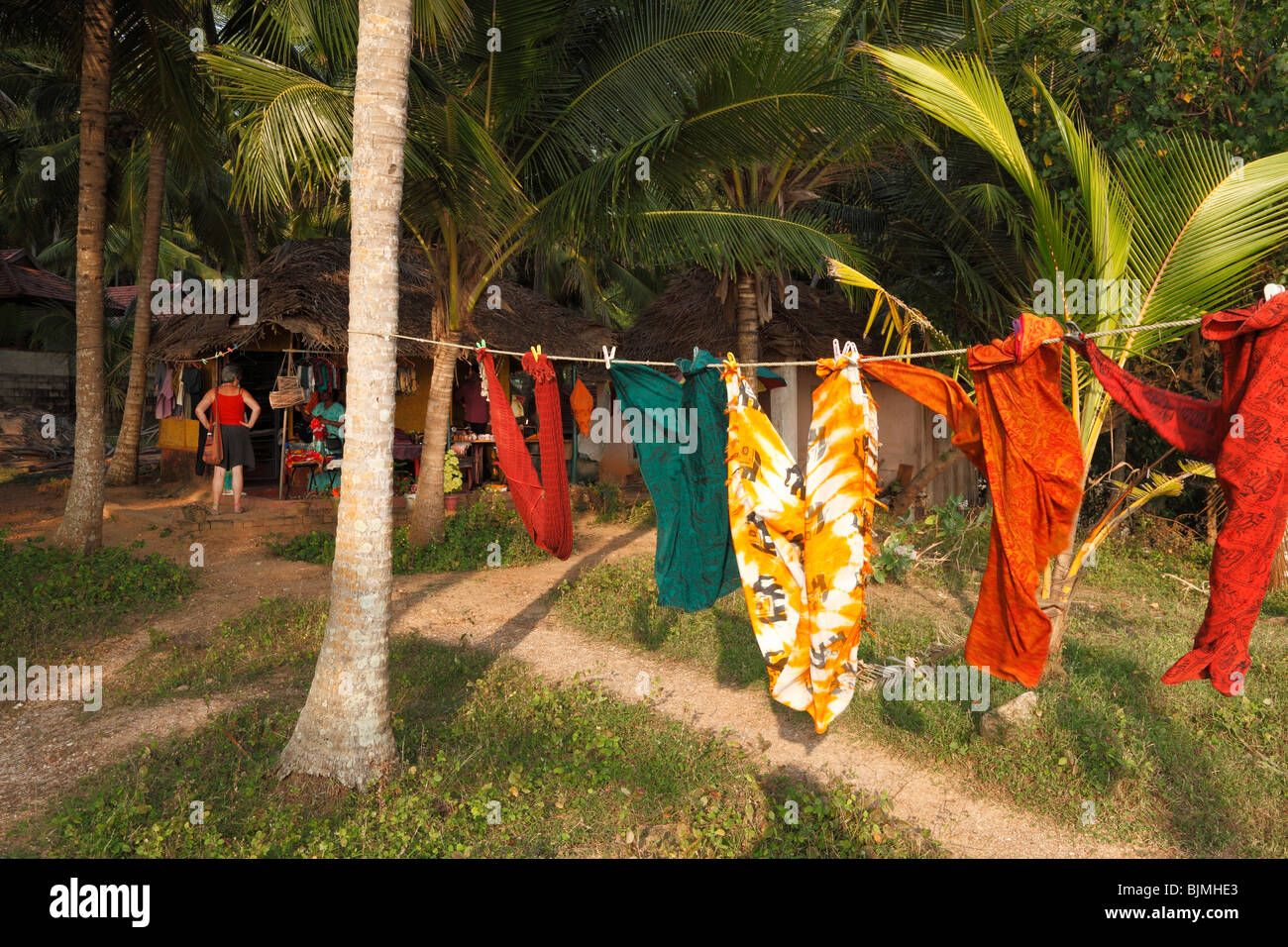 Stoffe, die an einer Wäscheleine hängen, Nähen Hütte unter Palmen, südlich von Kovalam, Kerala Zustand, Indien, Asien Stockfoto