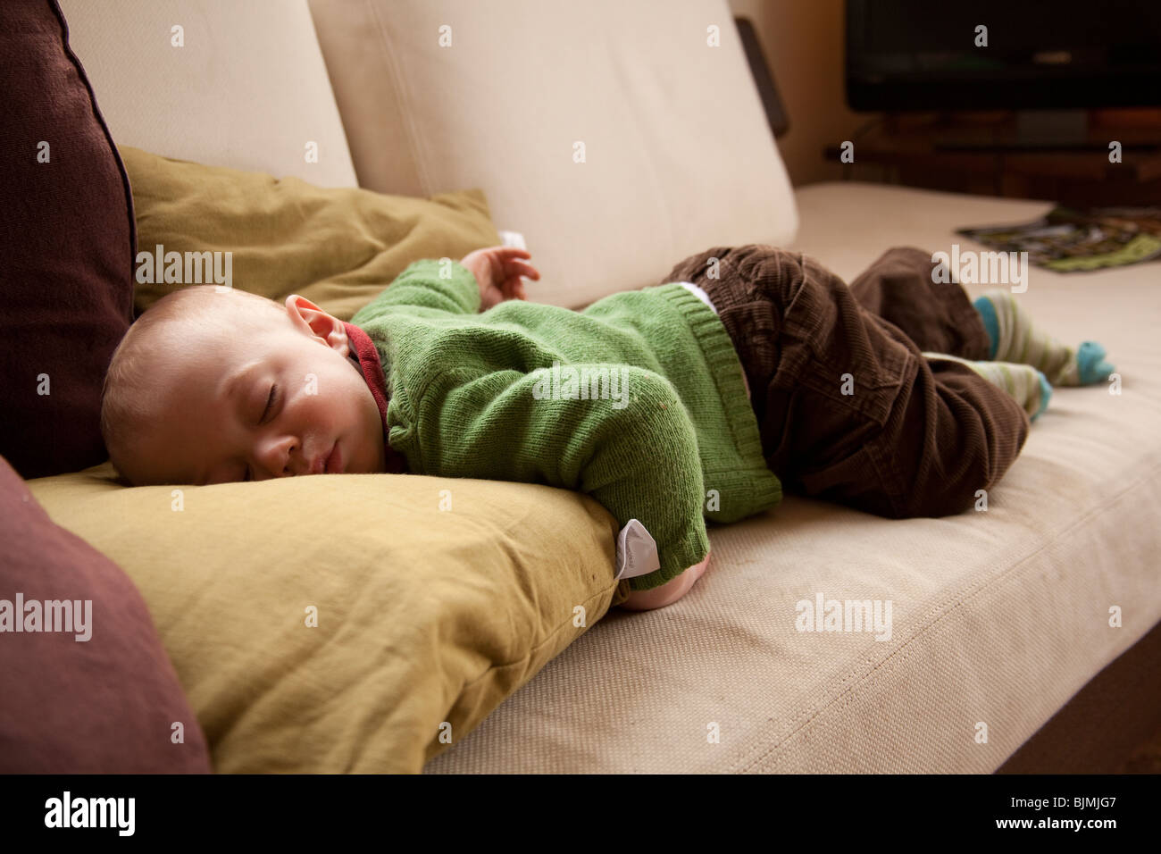 Baby Boy (elf Monate alt) schläft auf dem Sofa Hampshire England. Stockfoto