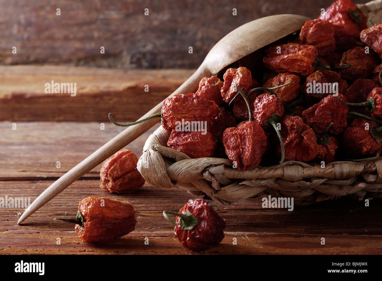 Mini-Paprika (Paprika) in einem Weidenkorb auf einem rustikalen hölzernen Hintergrund Stockfoto