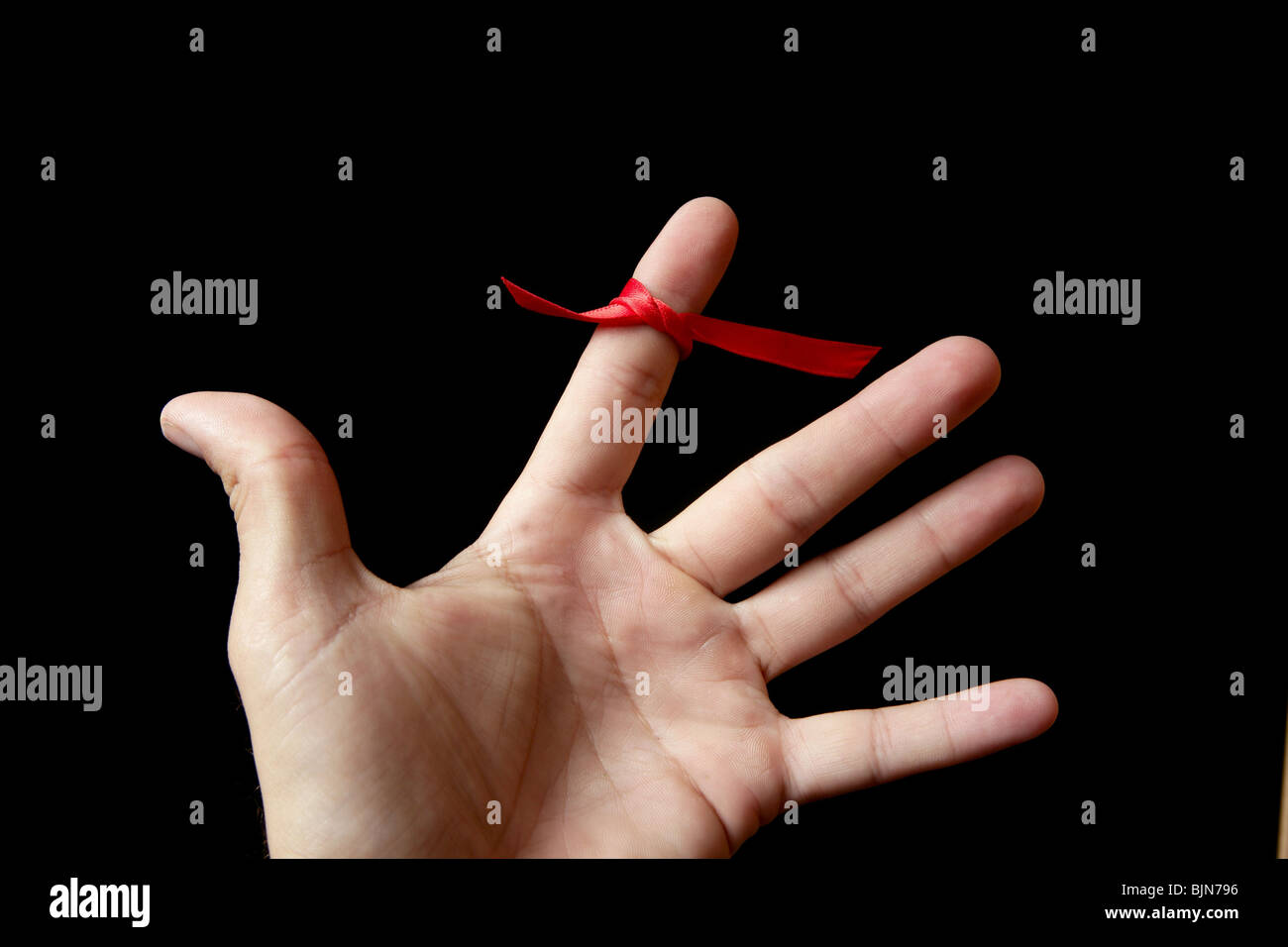 Red Tape Band, Schleife Band um menschliche Finger auf schwarzem Hintergrund Stockfoto