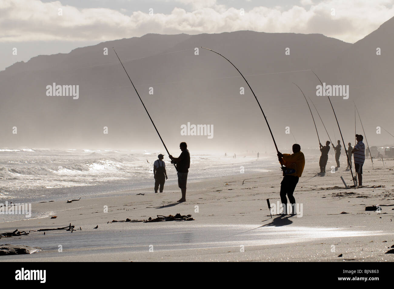 Männer Angeln vom Strand an der False Bay bei Muizenberg in der western Cape Südafrika gesehen aber die helle Sonne Stockfoto