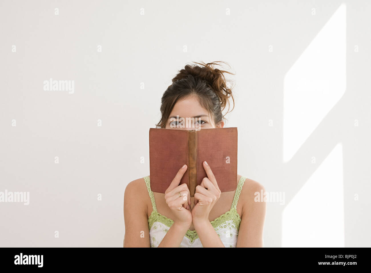 Frau versteckt sich hinter einem Buch Stockfoto