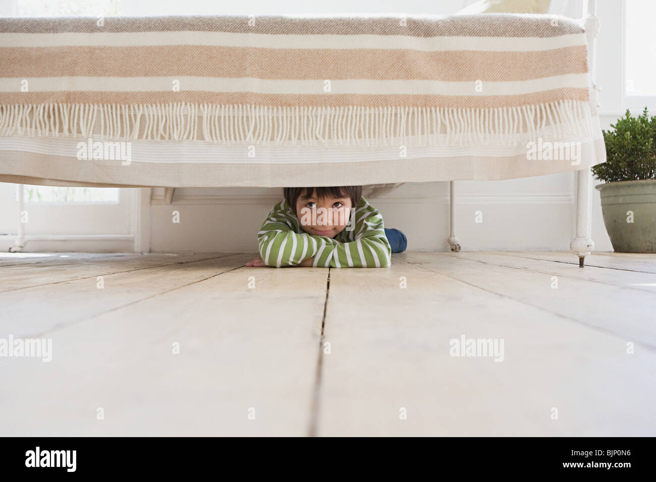 Junge versteckt unter dem Bett Stockfoto