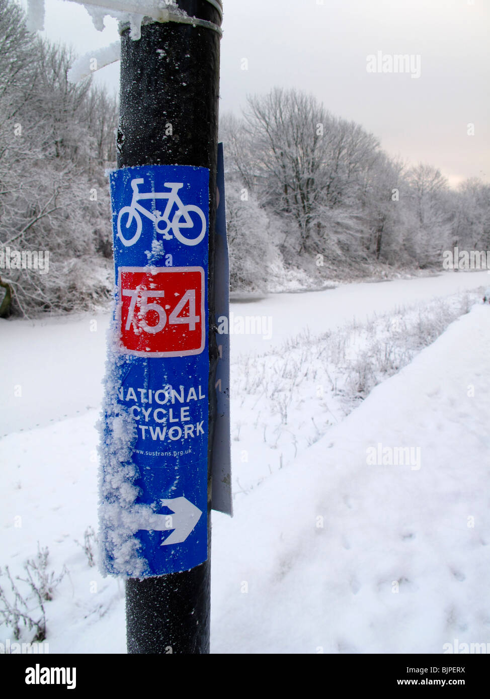 Radweg-Wegweiser durch Kanal im winter Stockfoto
