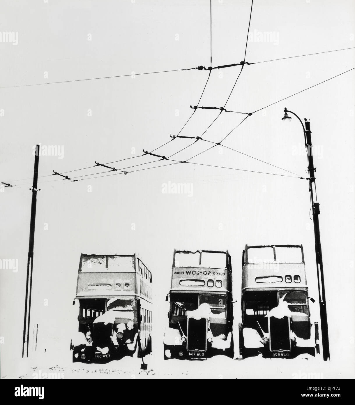 Drei alte Doppeldecker-Busse geparkt im Schnee in Wolverhampton unter elektrische Straßenbahn Drähte Stockfoto