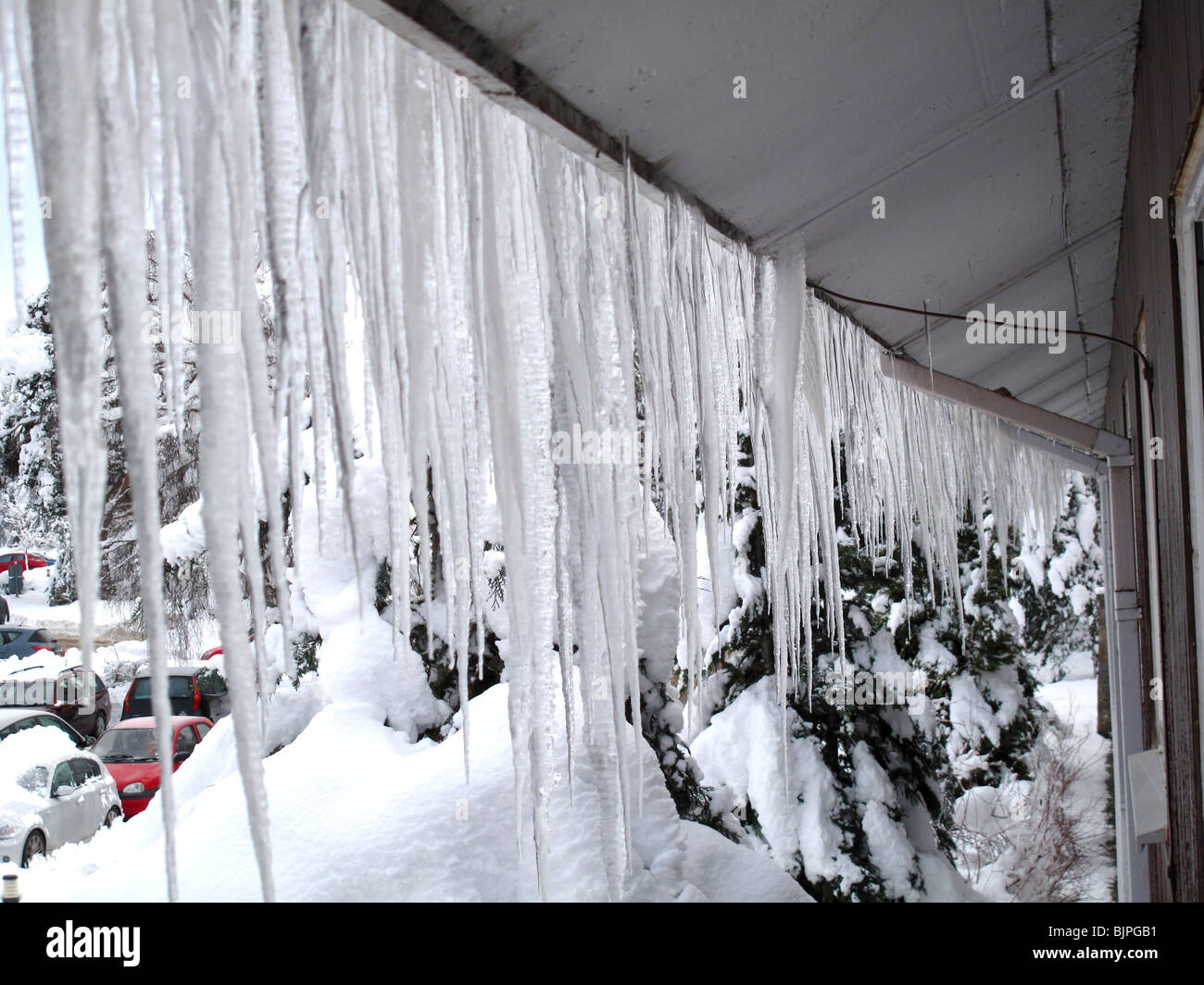 Eiszapfen hängen von Dachtraufe Stockfoto