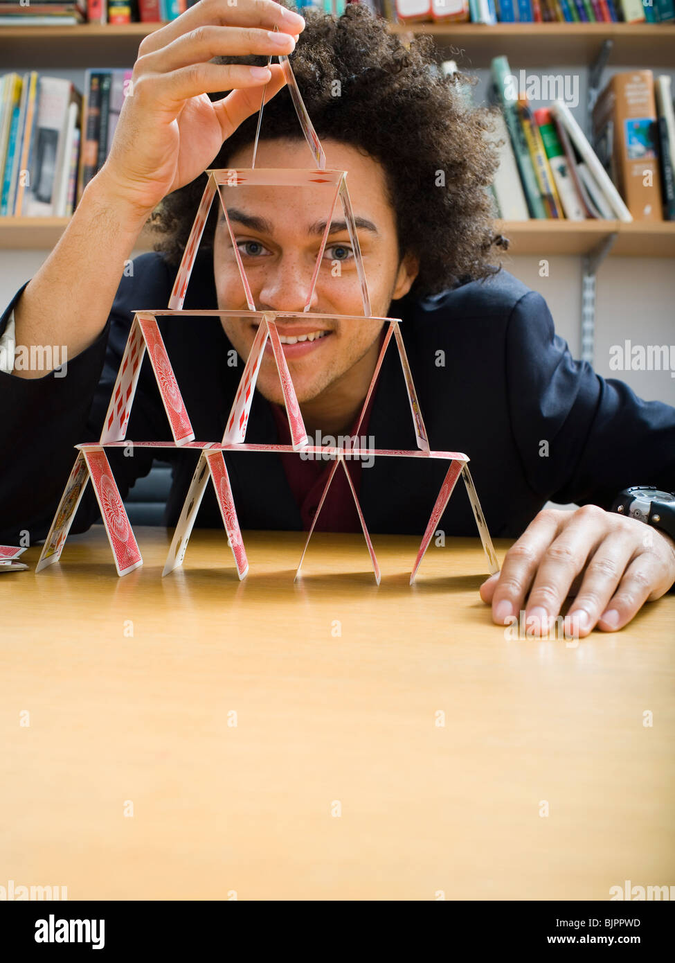 Mann, der eine Pyramide aus Spielkarten Stockfoto