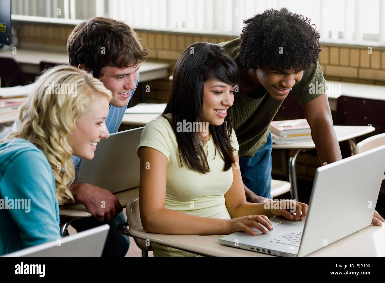 Vier Studenten drängten sich um einen Notebook-Computer. Stockfoto
