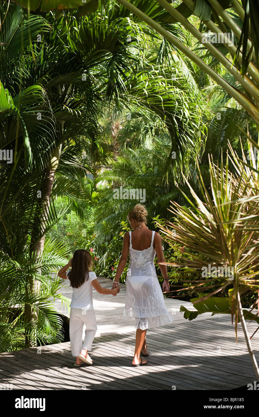 Mutter und Kind auf einem Holzsteg in einem tropischen Garten Stockfoto