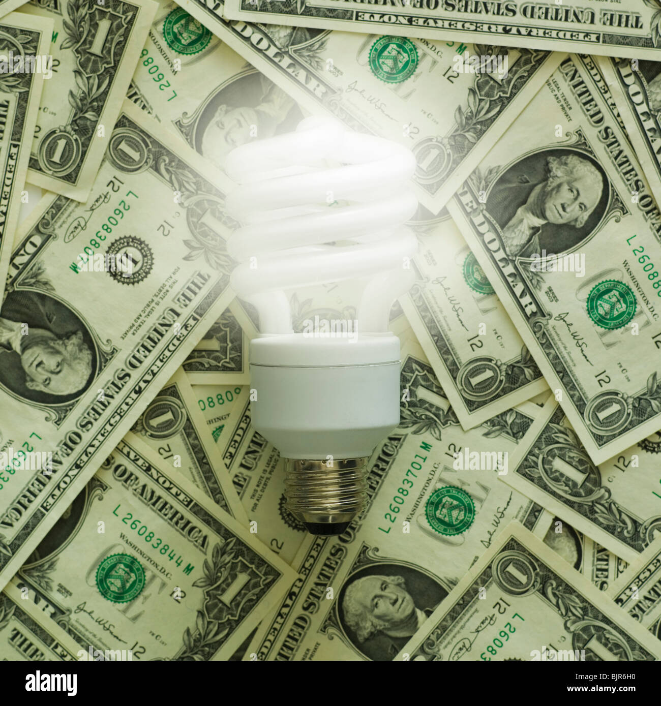 Glühbirne auf einen Haufen von Dollarnoten Stockfoto