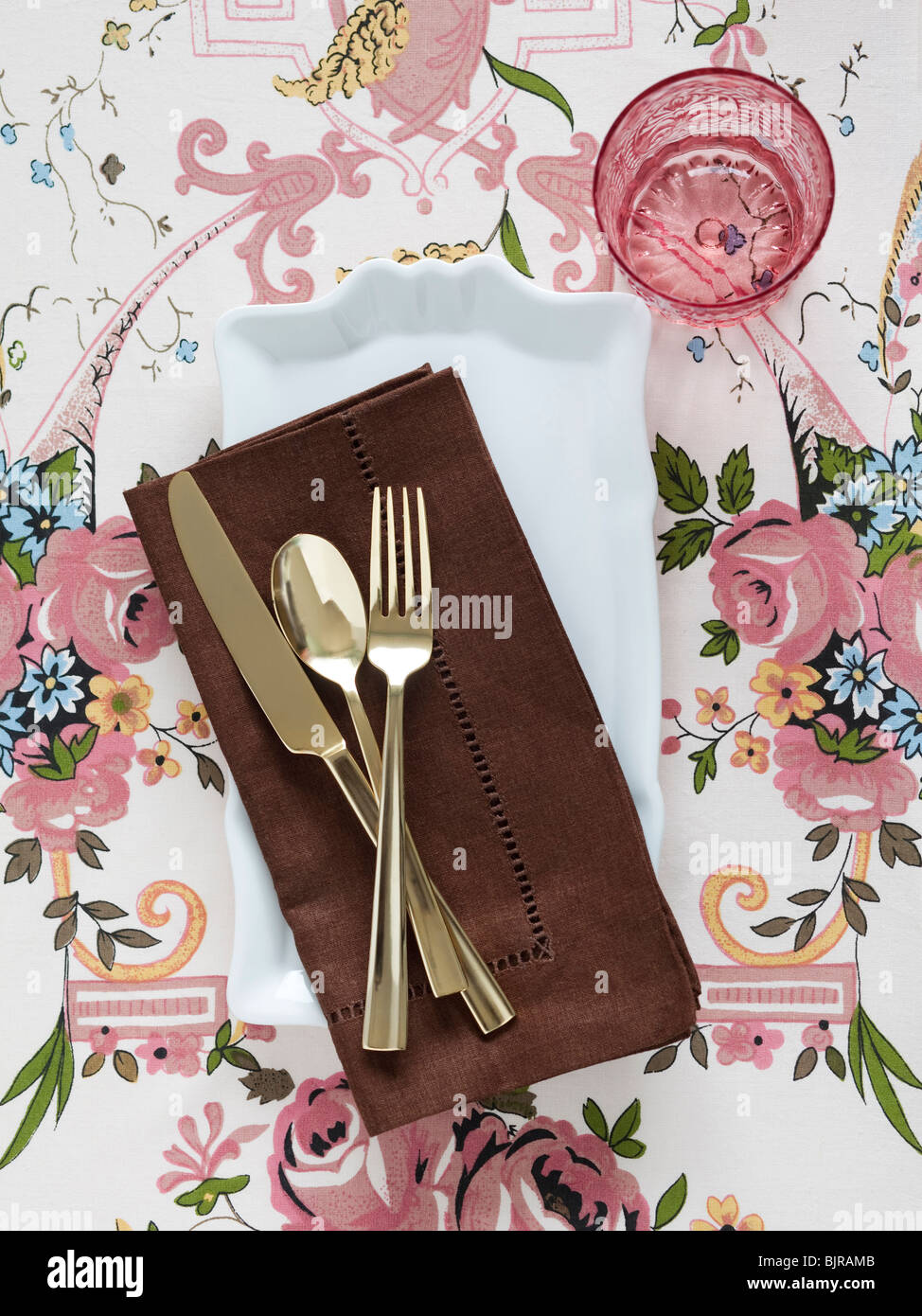 Teller mit Servietten und Besteck auf floral Tischdecke Stockfoto