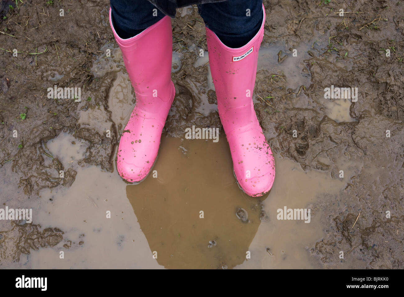 Ein paar helle Rosa Hunter Wellington (Gummistiefel) Stiefel Stand Schlamm  bespritzt, imprägniert in einer Pfütze Landschaft Stockfotografie - Alamy