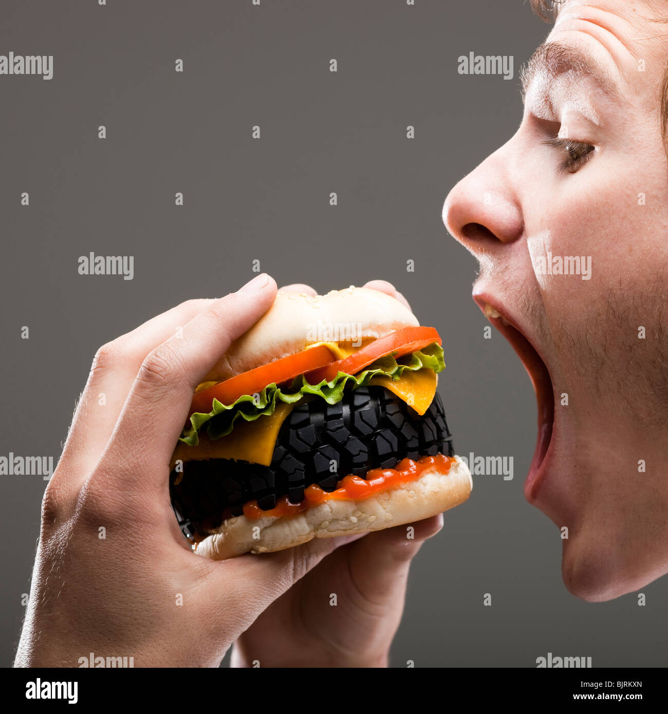 Seitenansicht des jungen Mannes über einen Reifen Hamburger beißen hautnah Stockfoto