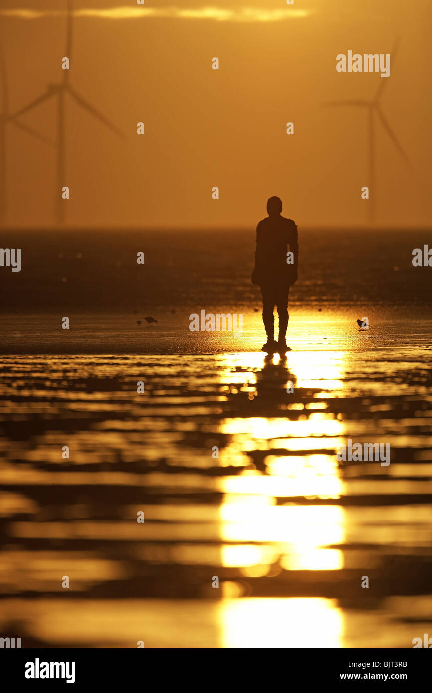 "Woanders" Sonnenuntergang, Windkraftanlagen und Antony Gormley Skulptur Mann Crosby Strand, Merseyside, England, UK Stockfoto