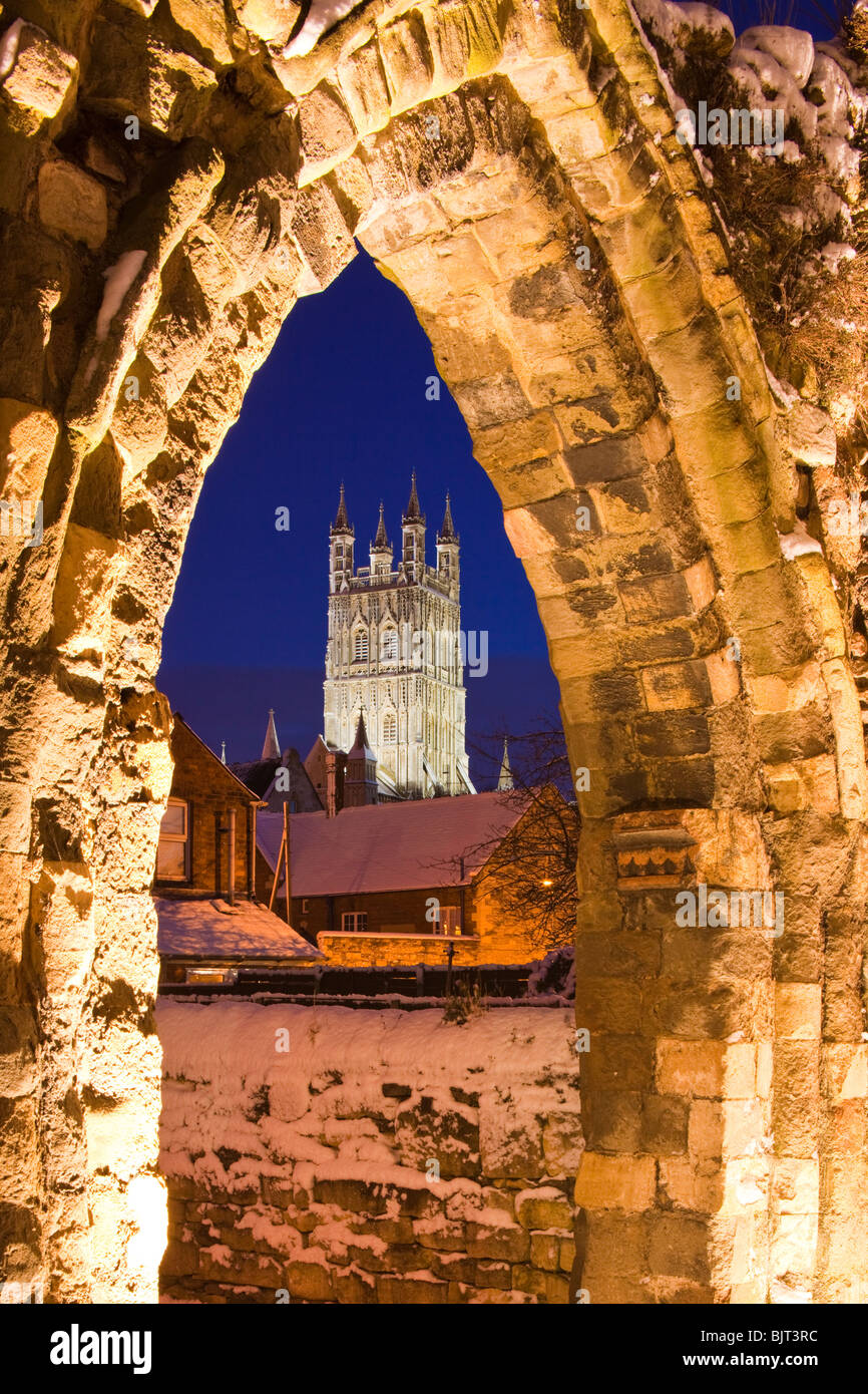 Gloucester Cathedral in der Abenddämmerung durch einen Bogen in den Ruinen des St. Oswalds Priorats an einem Winterabend gesehen - Gloucester UK Stockfoto
