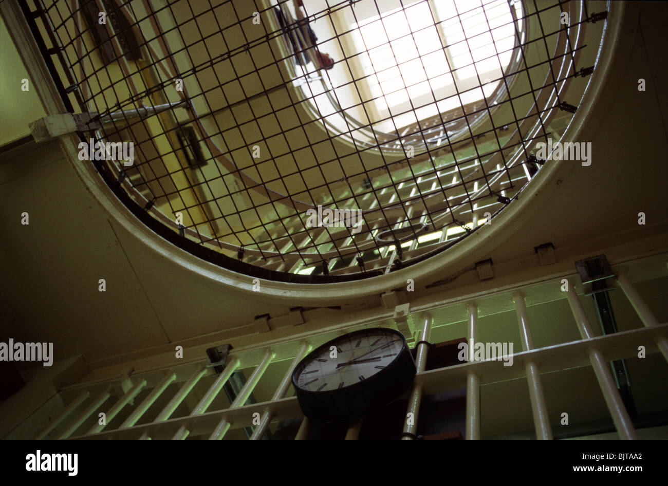 Blick auf Landungen, Maschendraht und vergitterten Tor bei HM Prison Cardiff, Wales, UK, mit einer Uhr. Stockfoto