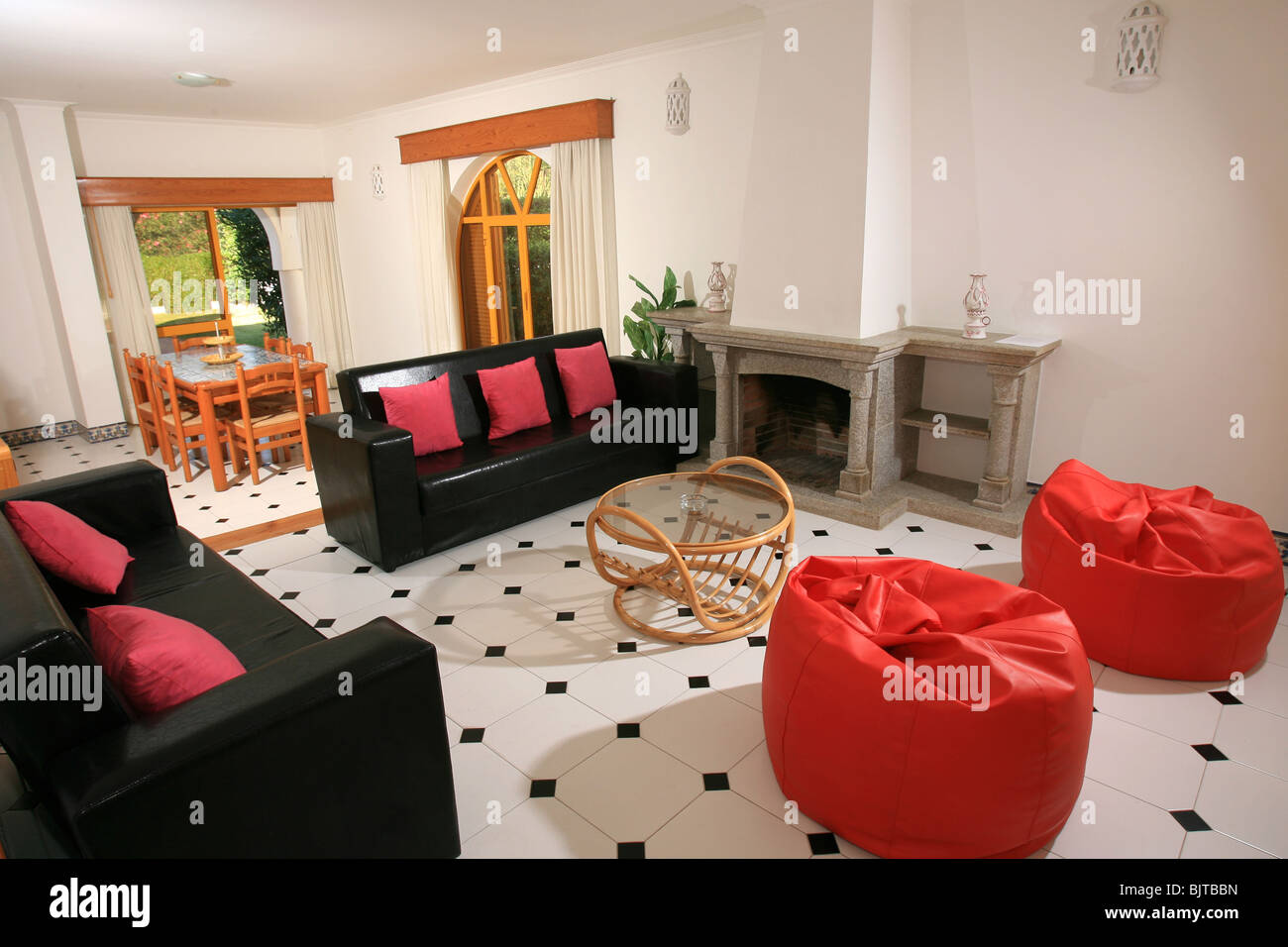 Helle moderne Loung und Esszimmer Interieur mit einem Ledersofa, Fliesenboden und rote Sitzsäcke Stockfoto