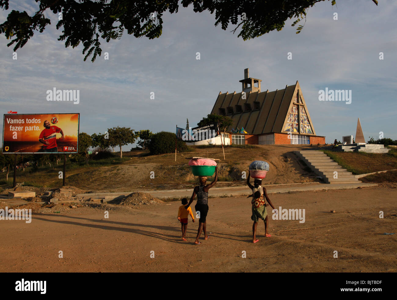 Frau tragen Kinder und Essen auf ihre Köpfe in der Stadt Sumbe verkaufen. Kwanza Sol, Angola, Afrika Stockfoto