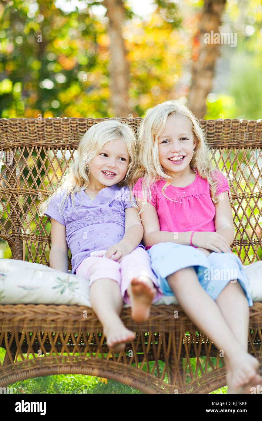 Schwestern sitzen auf Sitzplatz im Garten Stockfoto