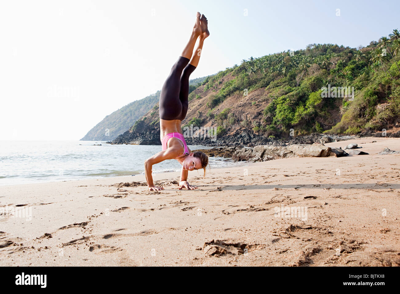 Frau macht Handstand am Strand Stockfoto