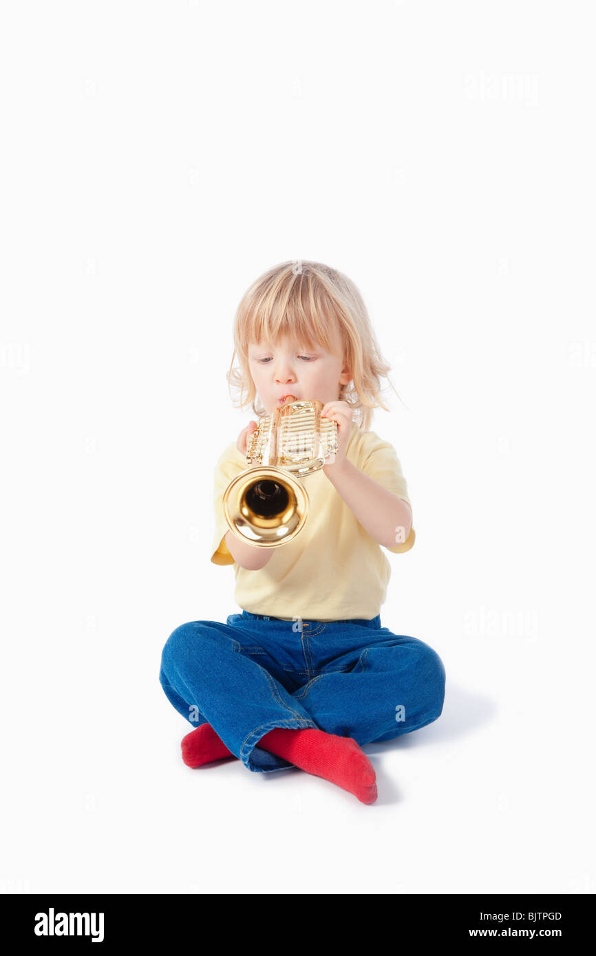 Junge mit langen blonden Haaren mit Spielzeug Trompete spielen Stockfoto