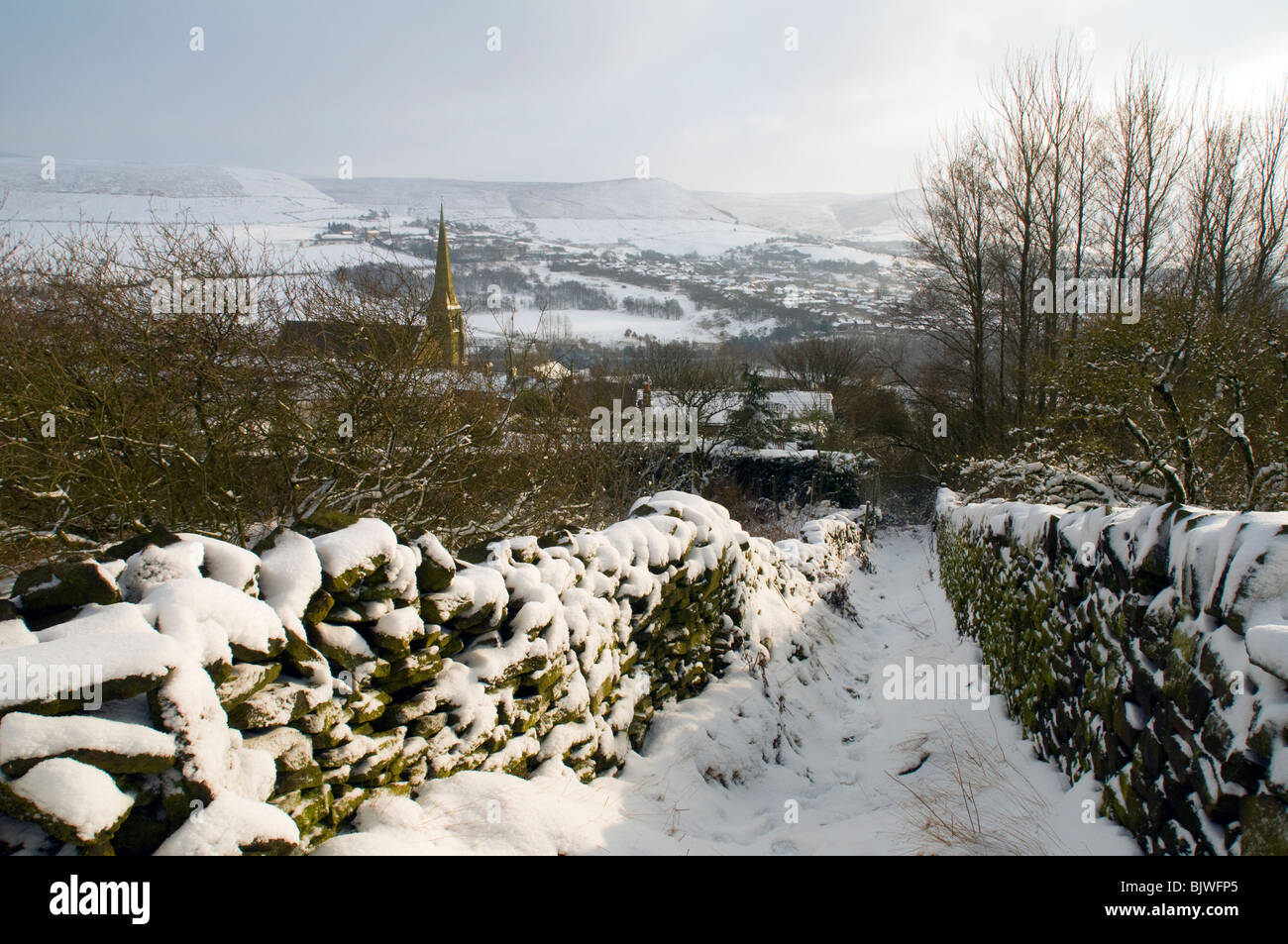 Schneebedeckte Wanderweg zwischen zwei Trockensteinmauern Mossley, Tameside, Greater Manchester, England, UK Stockfoto