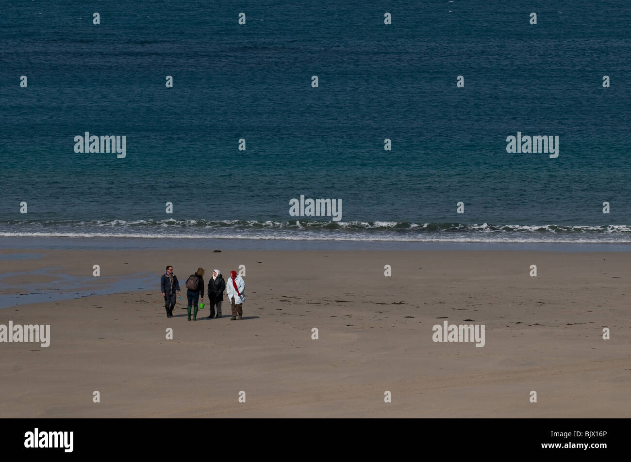 Vier Menschen zu Fuß am Strand von Sennen in Cornwall. Stockfoto