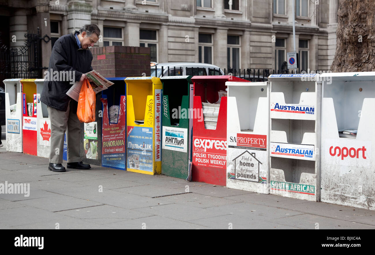 Eine Reihe von kostenlosen Zeitung Verteilungspunkte für fremdsprachige Publikationen auf einer Straße in central London, England, UK. Stockfoto