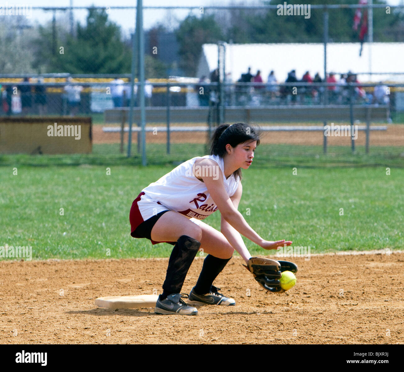 Mädchen-High School-Softball-Spiel. Ein Mädchen, das den Ball fängt. Stockfoto