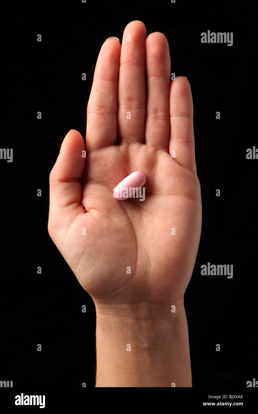 Eine weibliche Frau Hand hält eine Pille in der Handfläche von ihrer hand Stockfoto