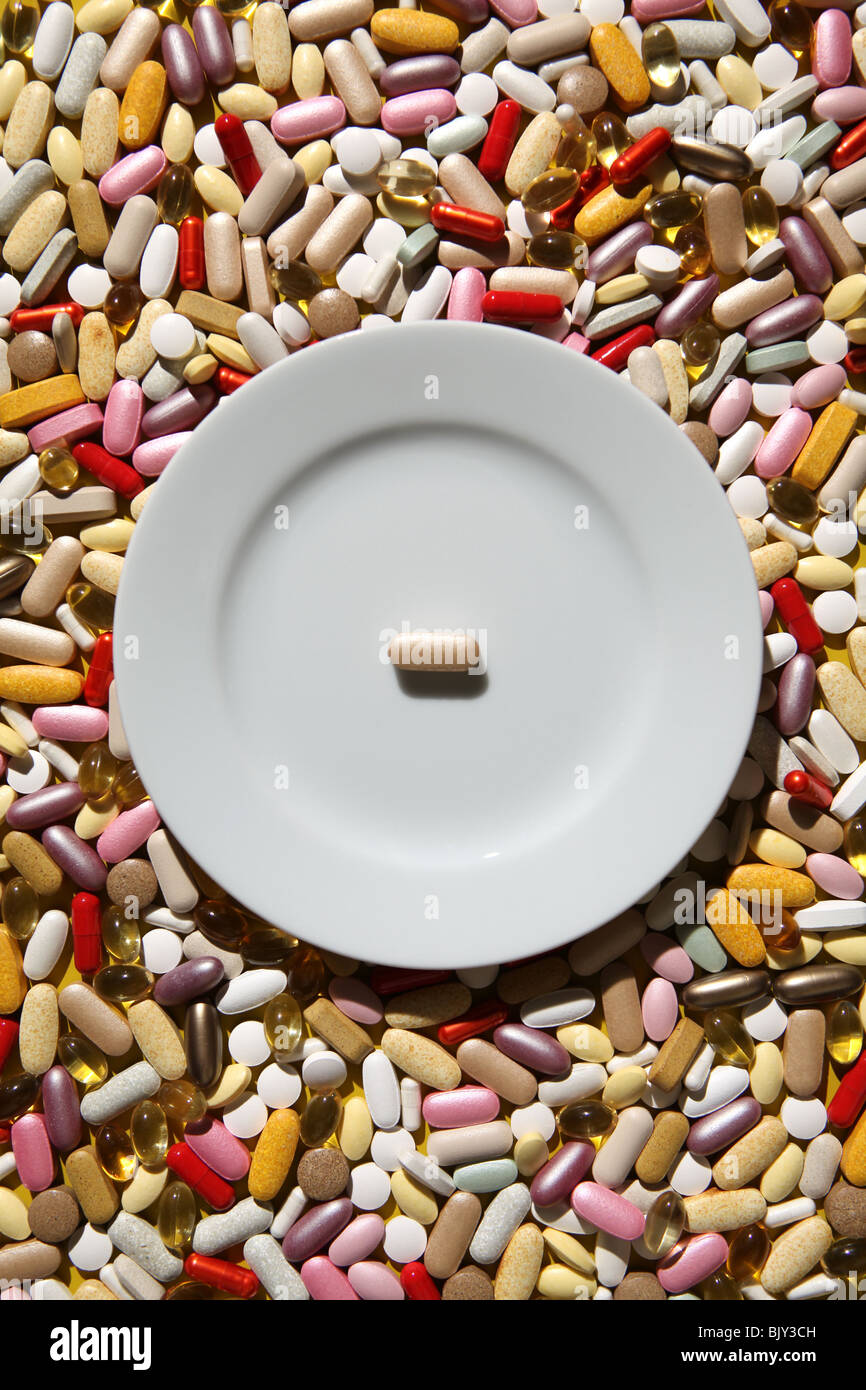 Eine leere weiße Teller mit einer Tablette vor dem Hintergrund der bunten Kapseln, Tabletten und Pillen Stockfoto