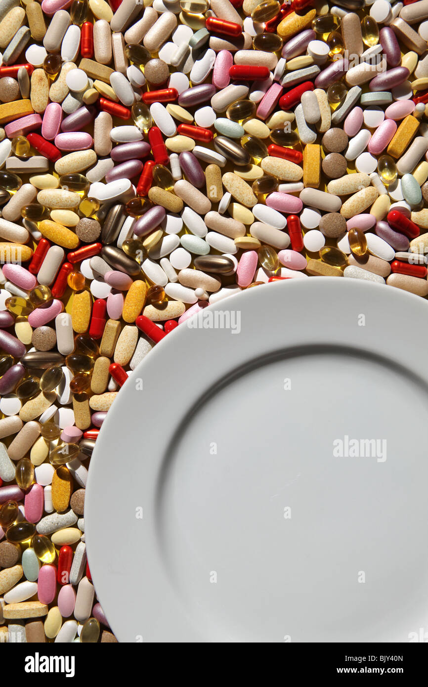Eine leere weiße Teller mit einem Hintergrund von bunten Kapseln, Tabletten und Pillen Stockfoto