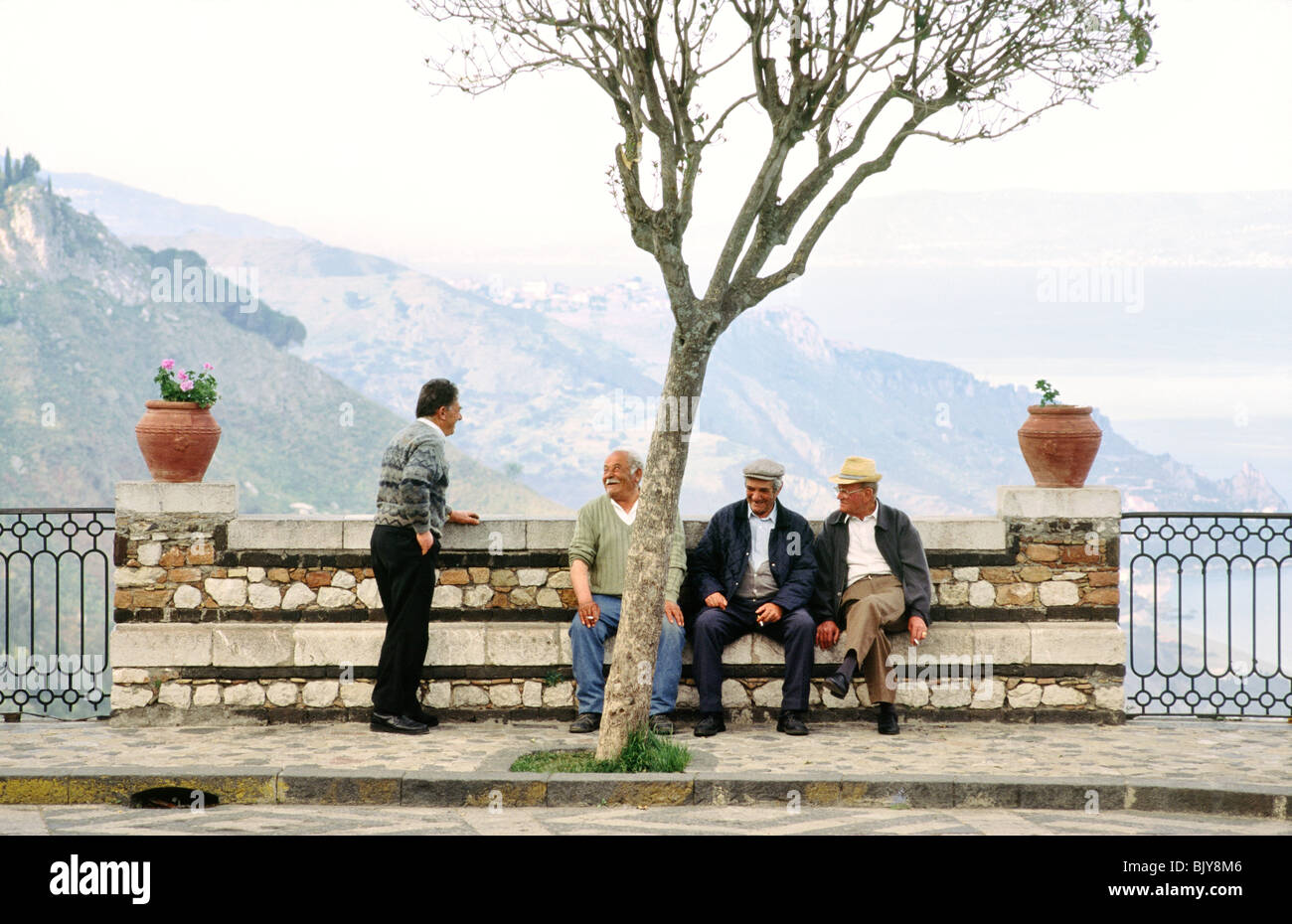 Sizilien, Italien. Männer im Chat auf dem Platz des Dorfes von Castel Mola in der Nähe von Taormina Stockfoto