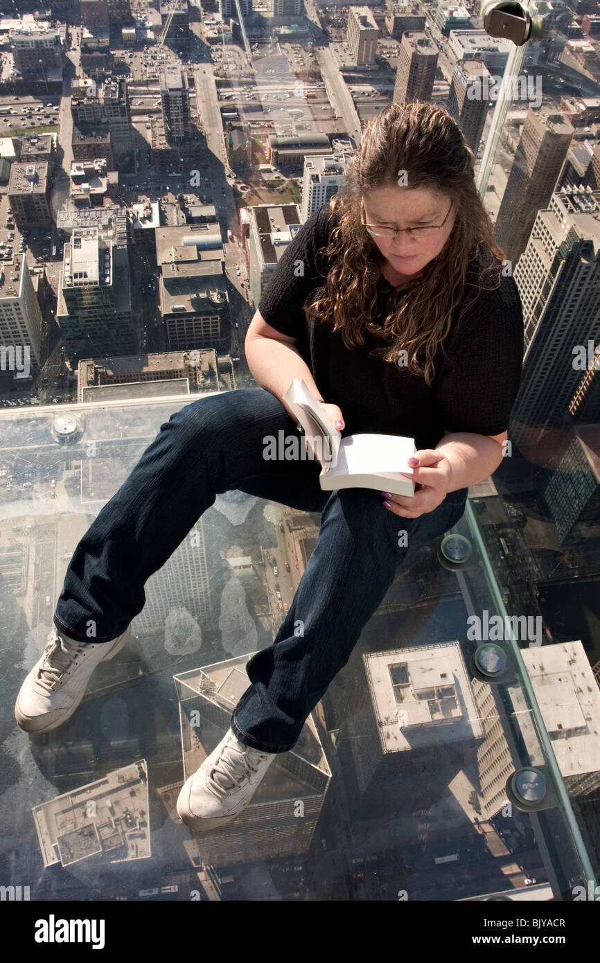 Die Sims - Frau liest auf der Aussichtsplattform (Skydeck) auf der Oberseite (ehemaliger Sears) Willis Tower in Chicago, Illinois, USA Stockfoto