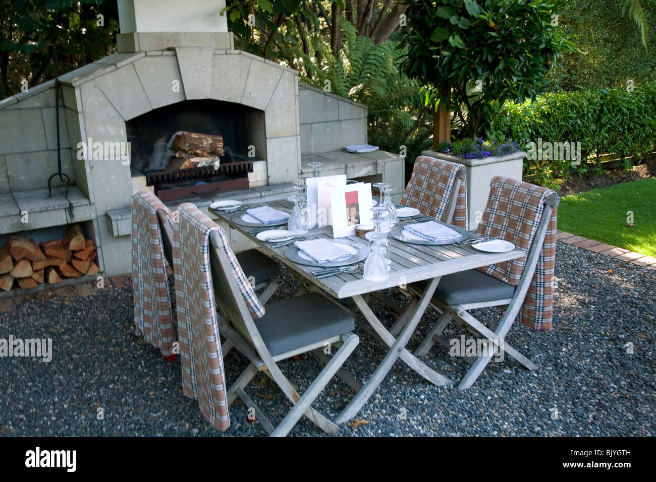 Eine Tabelle ist im Sommer für vier Gäste vor einer Feuerstelle gesetzt. Stockfoto
