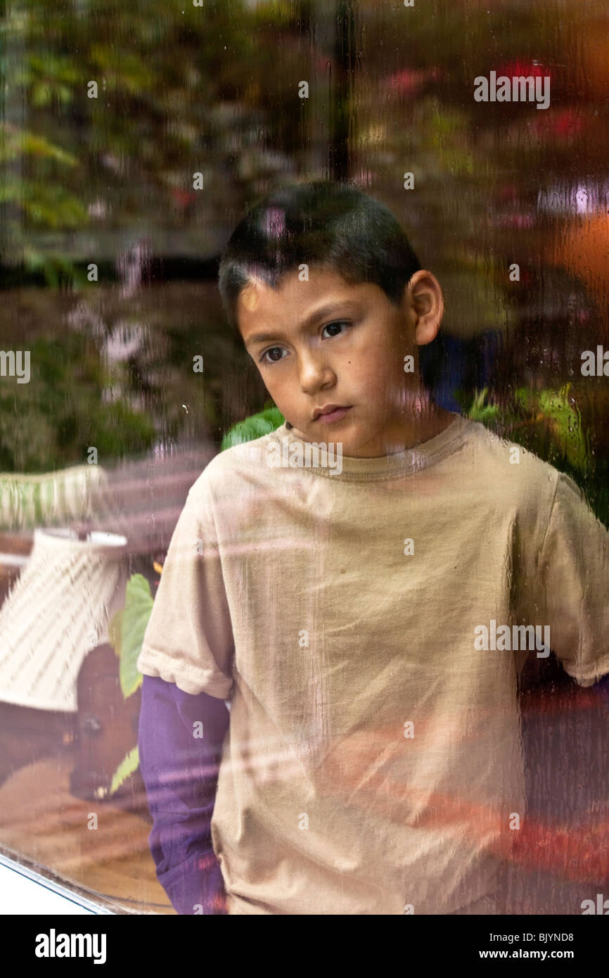 multikulturelle Kind 9-10 Jahre Jahre Alter spanischer Junge Blick durch ein Fenster an einem regnerischen day.MR © Myrleen Pearson Stockfoto