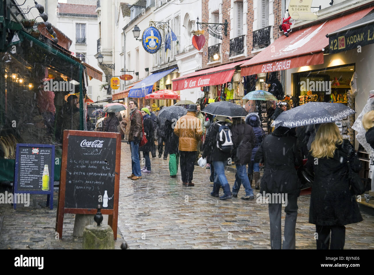 Menschen zu Fuß unter dem Schnee in Rue Norvin, Viertel Montmartre in Paris, Frankreich. Stockfoto