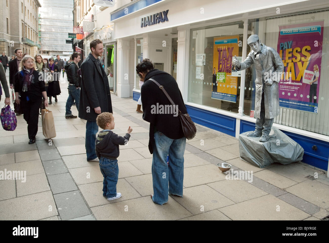 Eine Straße Entertainer gemalt als eine silberne Statue, mit Kindern, Lion Yard, Cambridge, UK Stockfoto