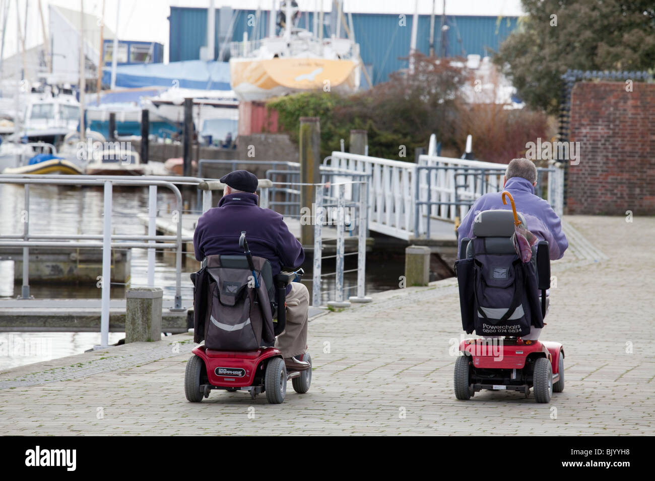 Zwei Männer im motorisierten Rollstuhl am Kai von Lymington. Stockfoto