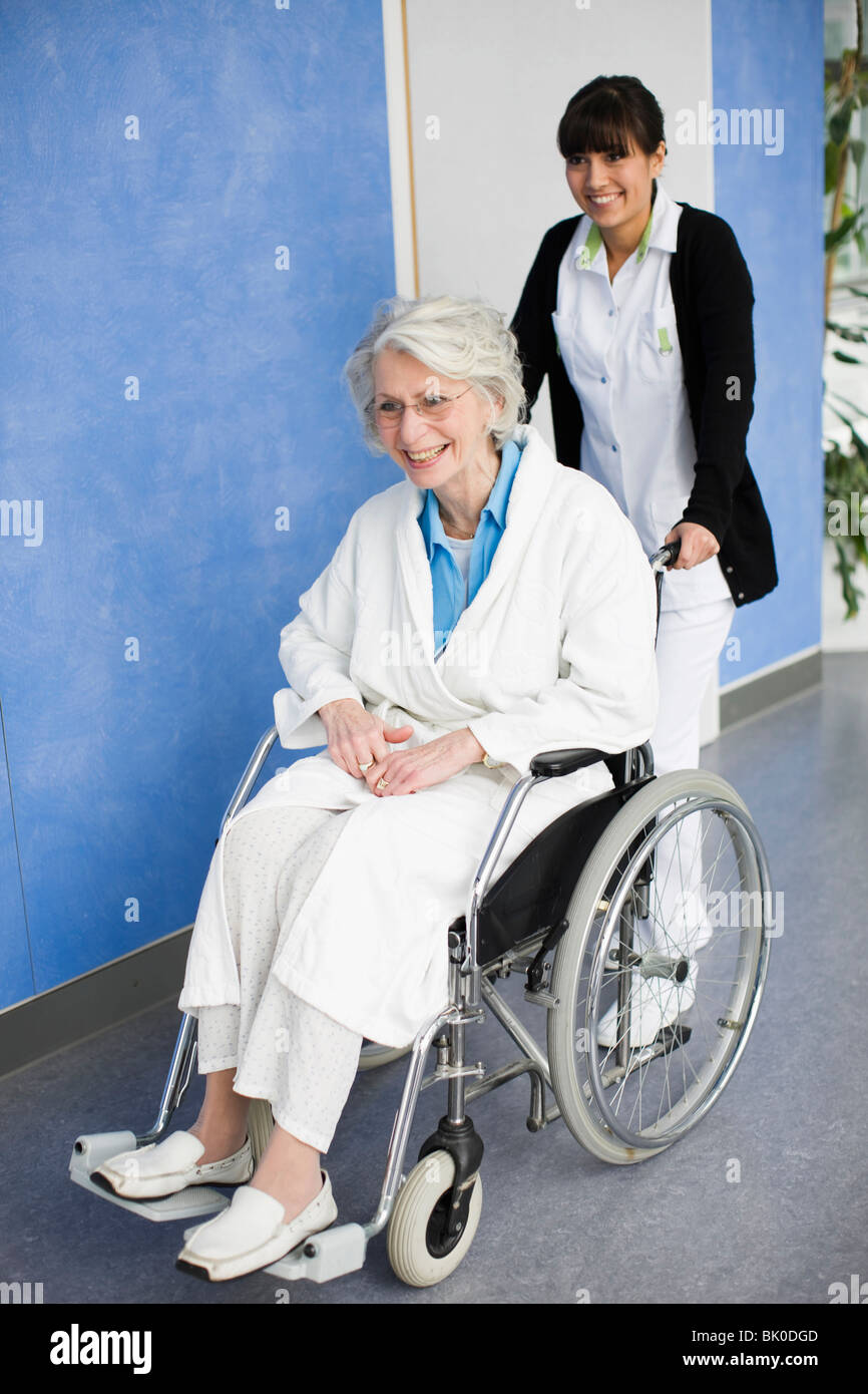 Alte Frau in einem Rollstuhl und Krankenschwester Stockfoto