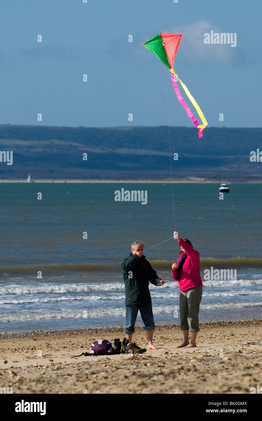 Ein paar, einen Kite am Strand in Bournemouth, windigen Tag im Frühjahr starten. Stockfoto