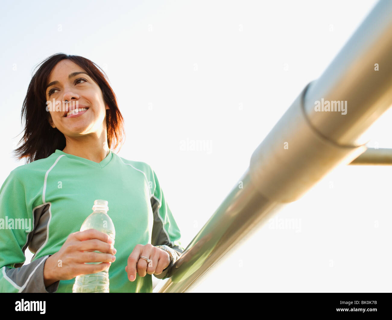 Gemischte Rassen Frau Trinkwasser durch Geländer Stockfoto