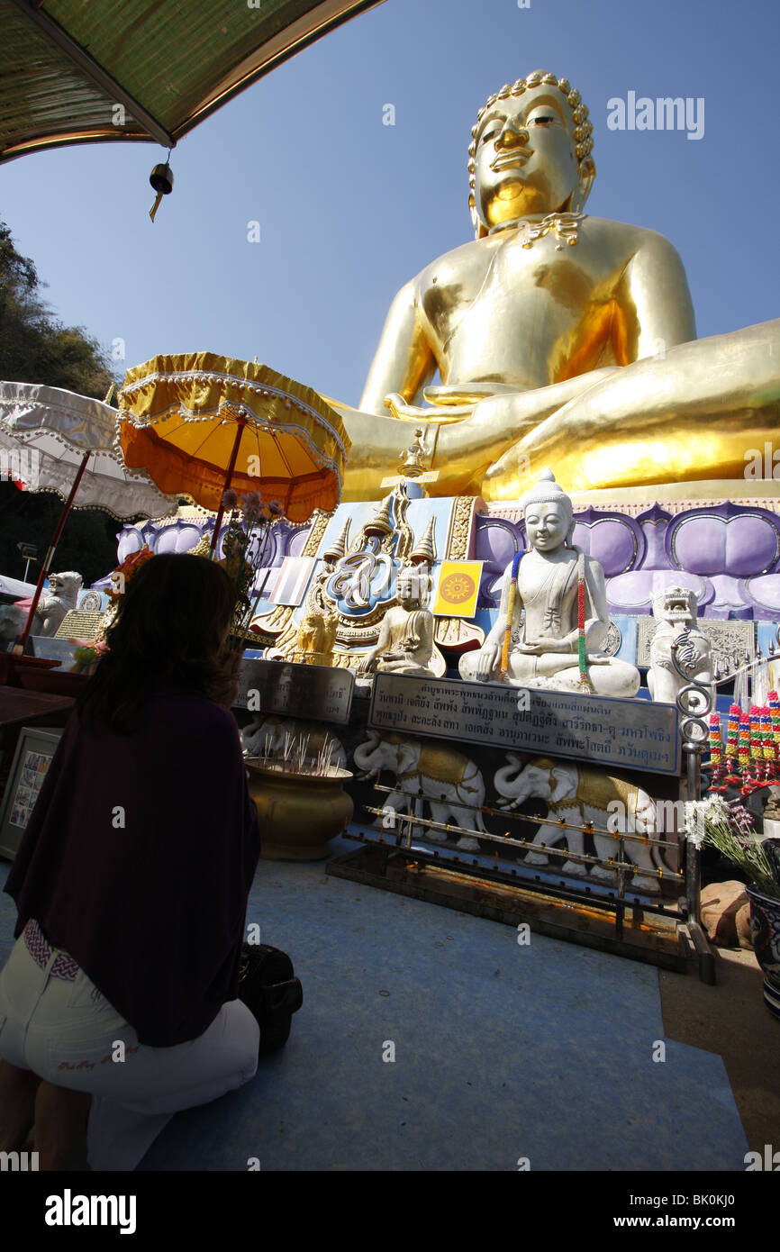 Eine Frau betet vor einem riesigen goldenen Buddha im Sop Ruak, The Golden Triangle, durch den Mekong im Norden Thailands Stockfoto