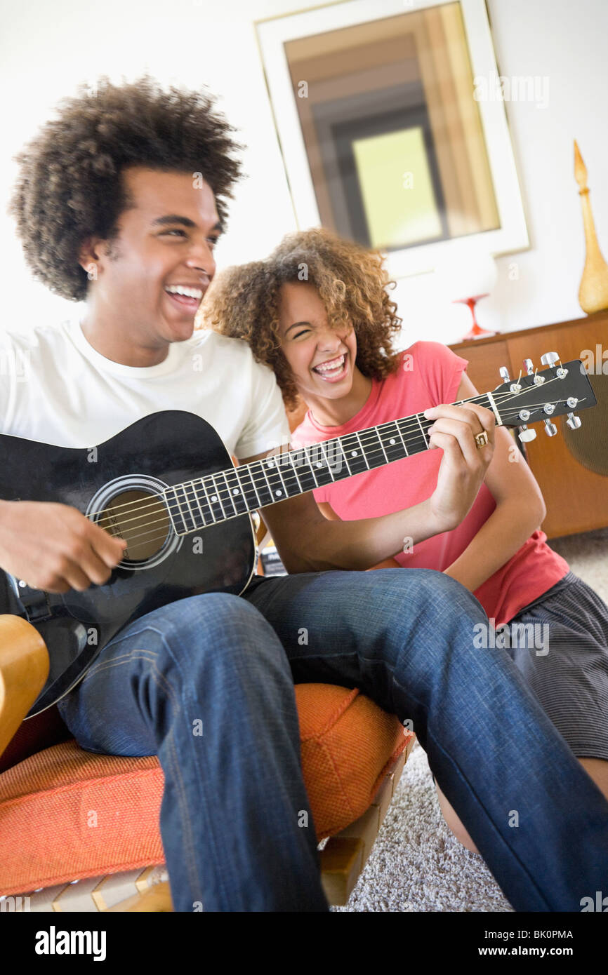 Frau, lachen, während Freund Gitarre spielt Stockfoto