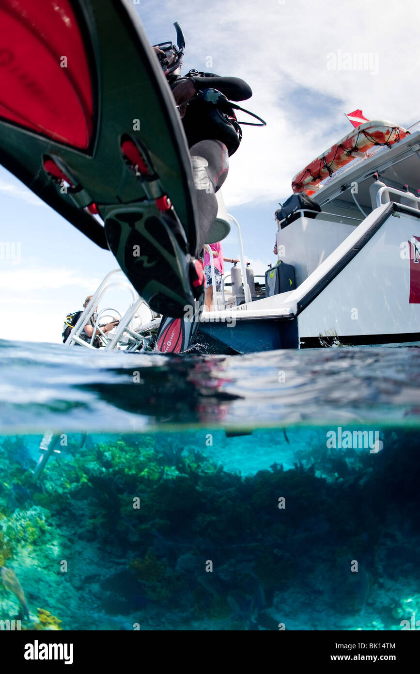 Scuba Diver gelangt Wasser vom Boot über großen Schritt Eintrag. Stockfoto