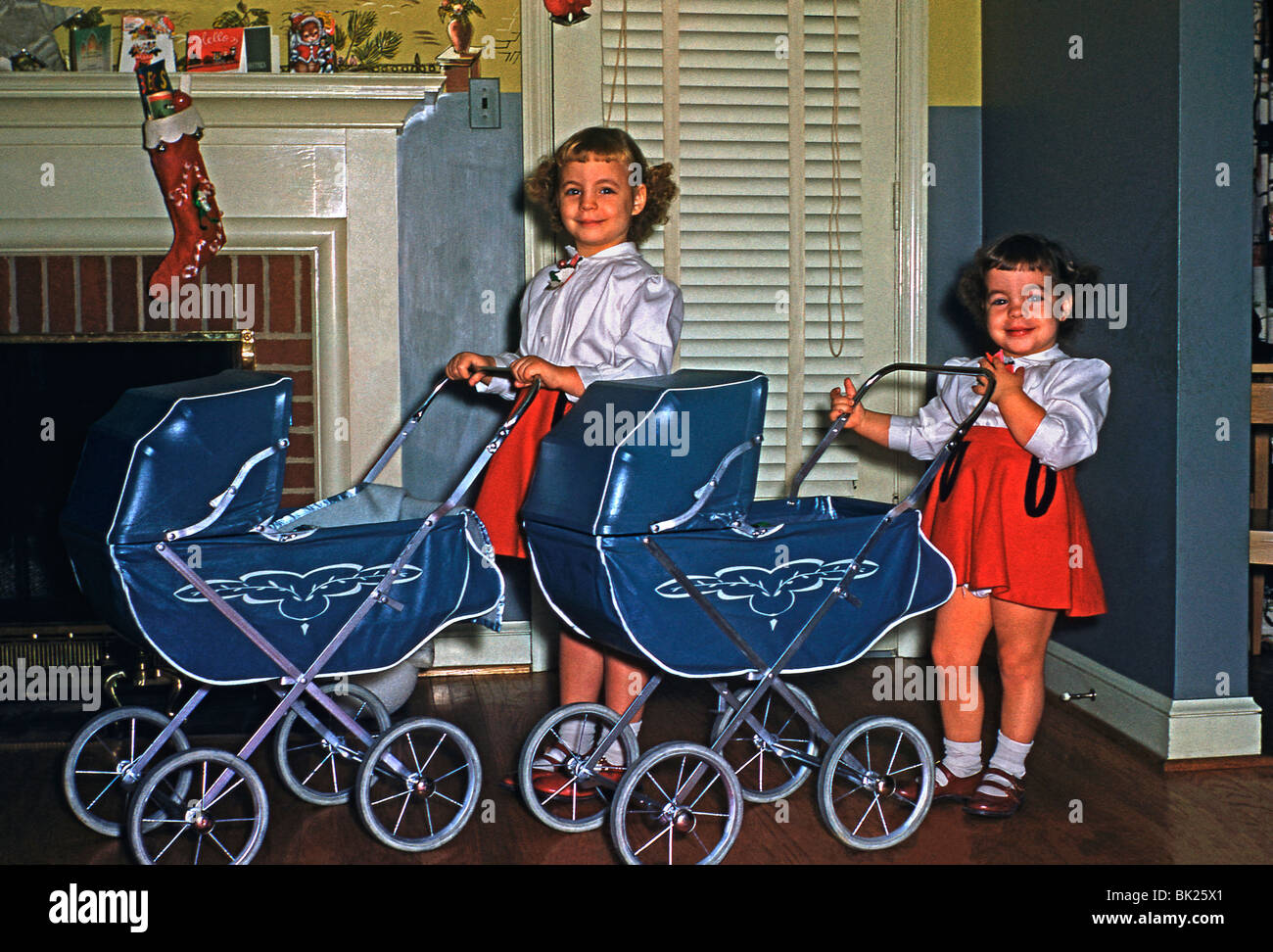 Zwei Mädchen posieren mit ihrem neuen Spielzeug Kinderwagen zu Weihnachten in den USA in den 1950er Jahren Stockfoto